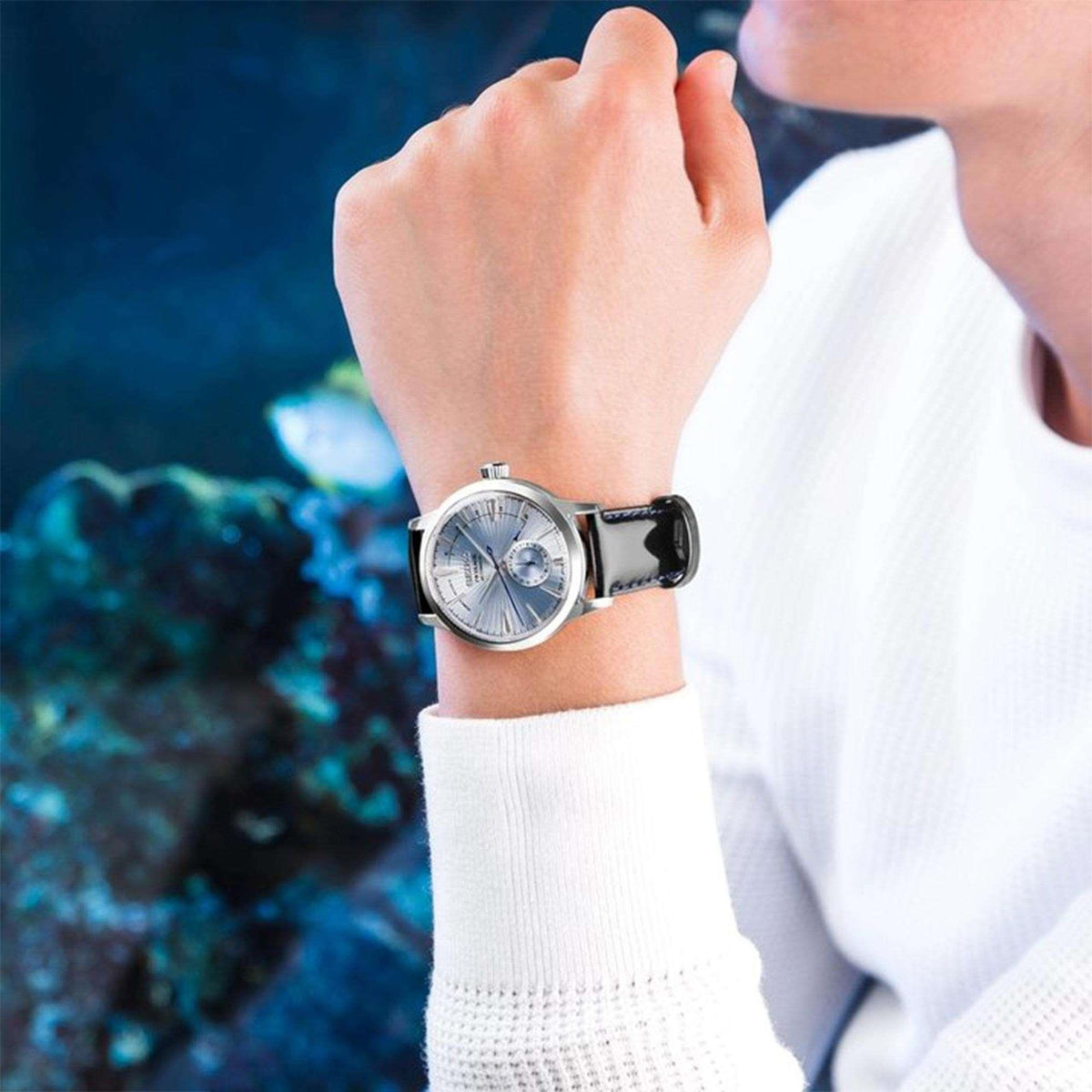 Men’s wristwatch with silver dial, black leather strap, and round steel case