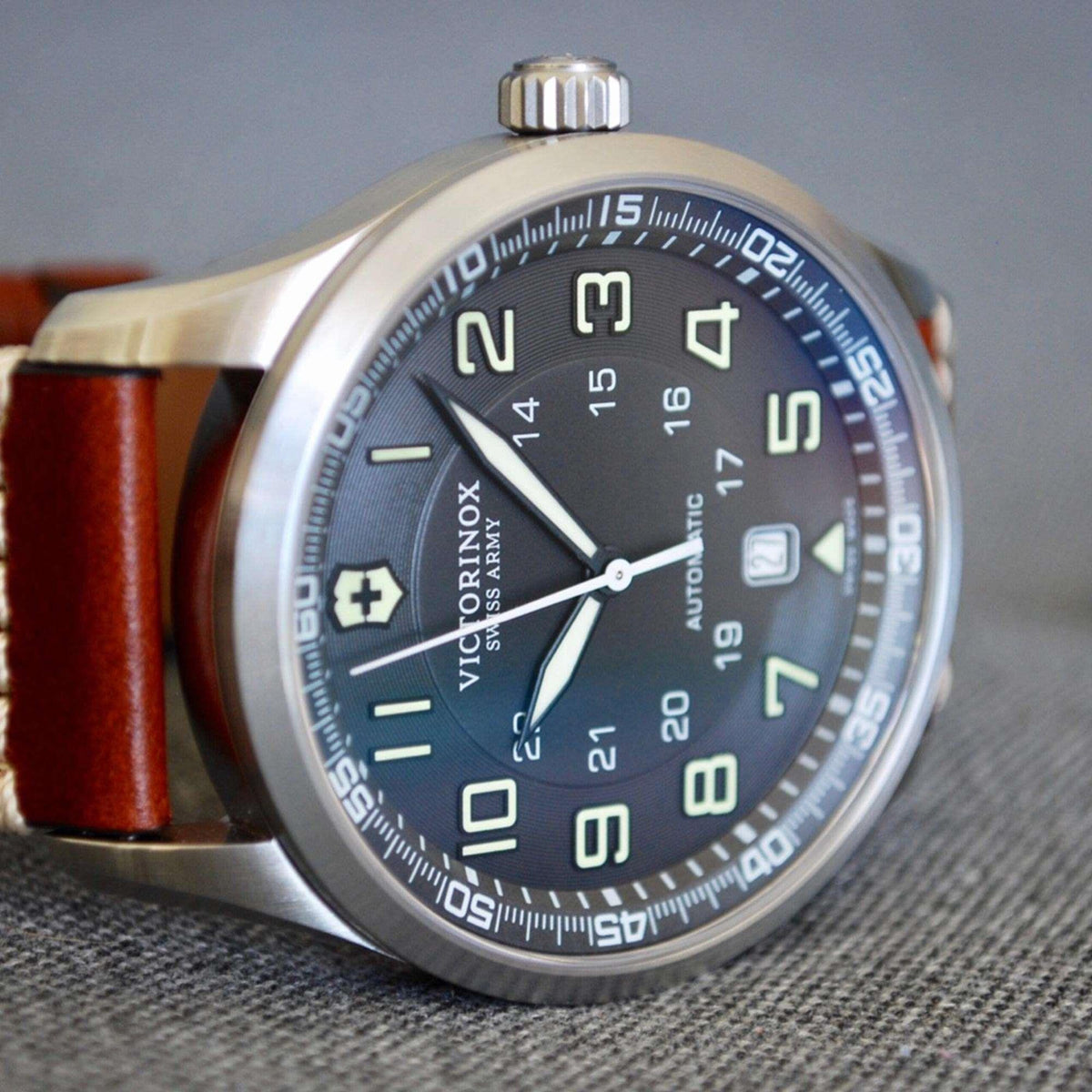 Men's mechanical wristwatch close-up of dark dial, luminous numerals, leather strap
