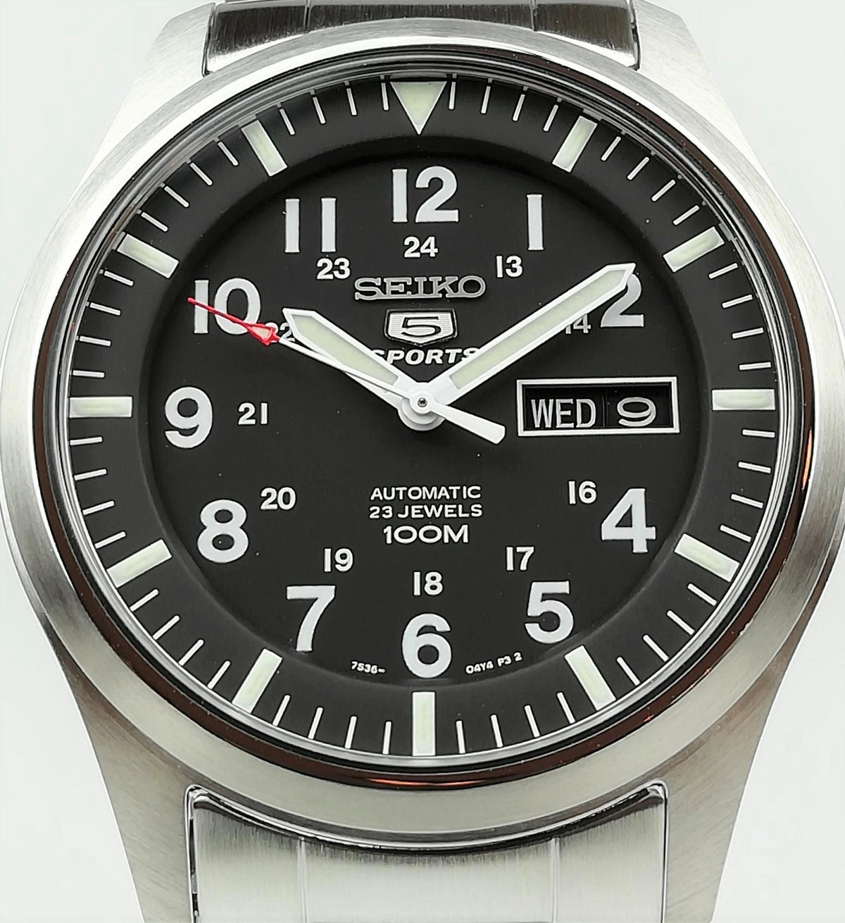 Seiko 5 Sports watch face closeup: black dial with WED date window and steel case