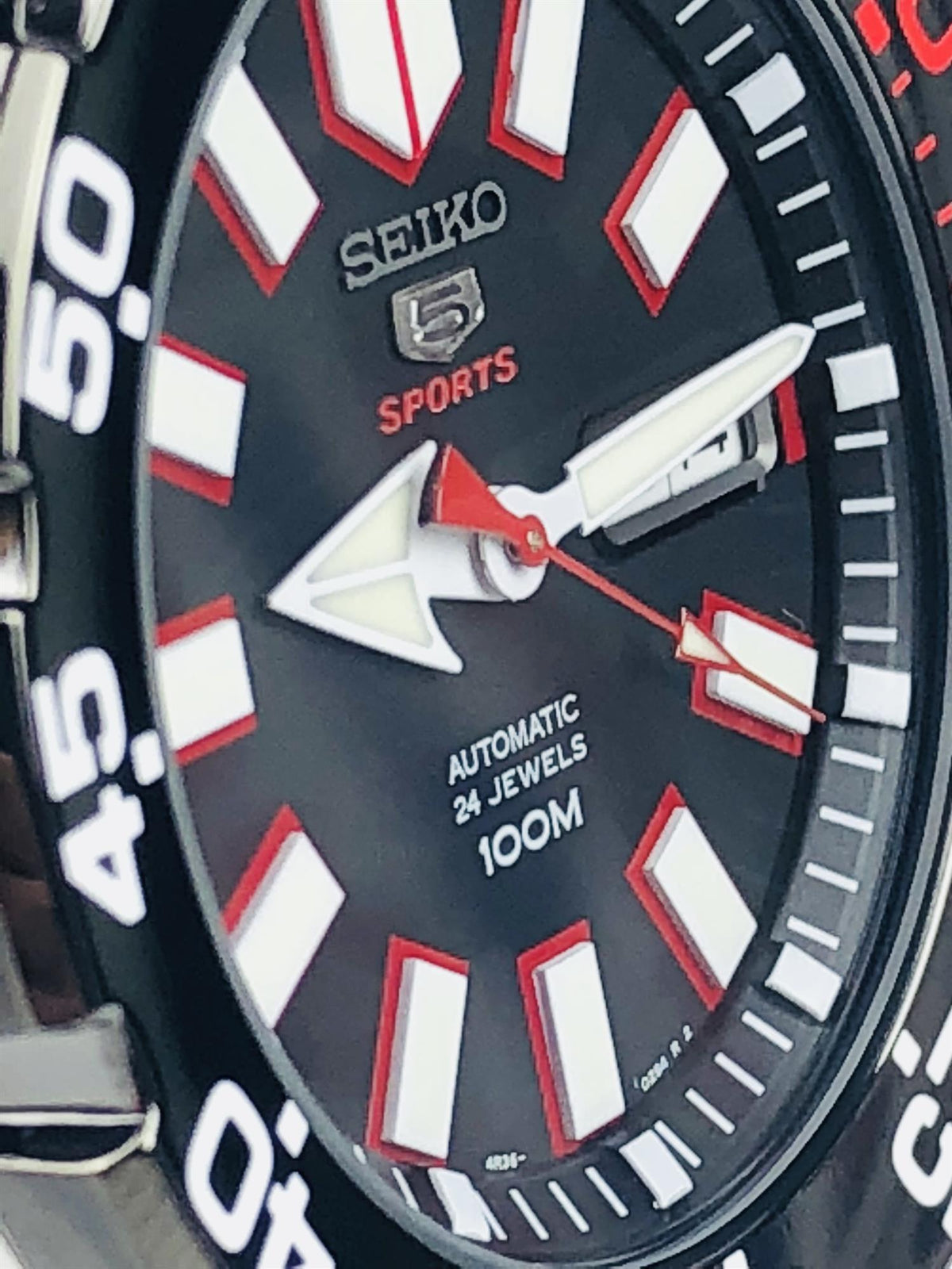 Close-up Seiko Sports dial detail, black face, red indices, red seconds hand