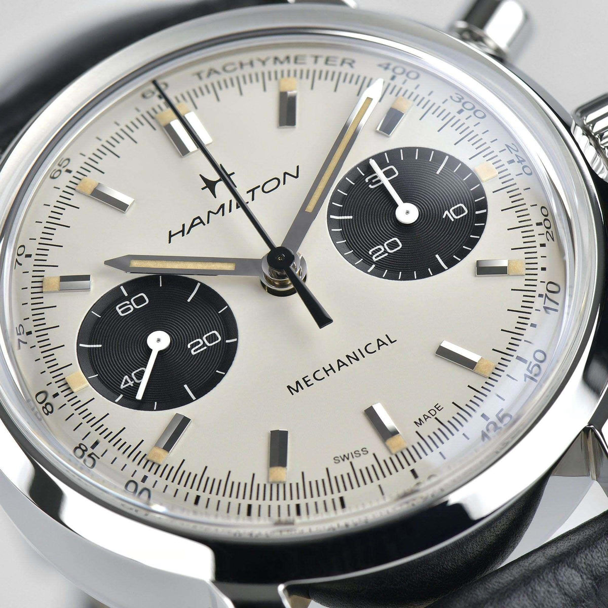 Hamilton chronograph watch dial close-up: white face with tachymeter scale, black subdials