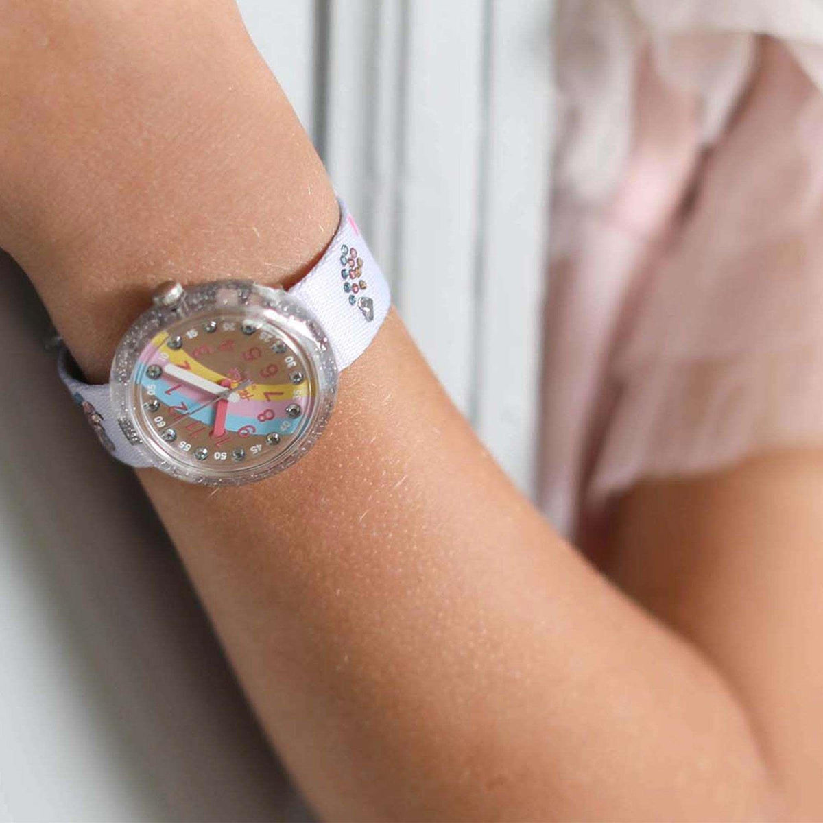 Flik Flak kids quartz wristwatch close-up on wrist, silver glitter bezel, rainbow numerals