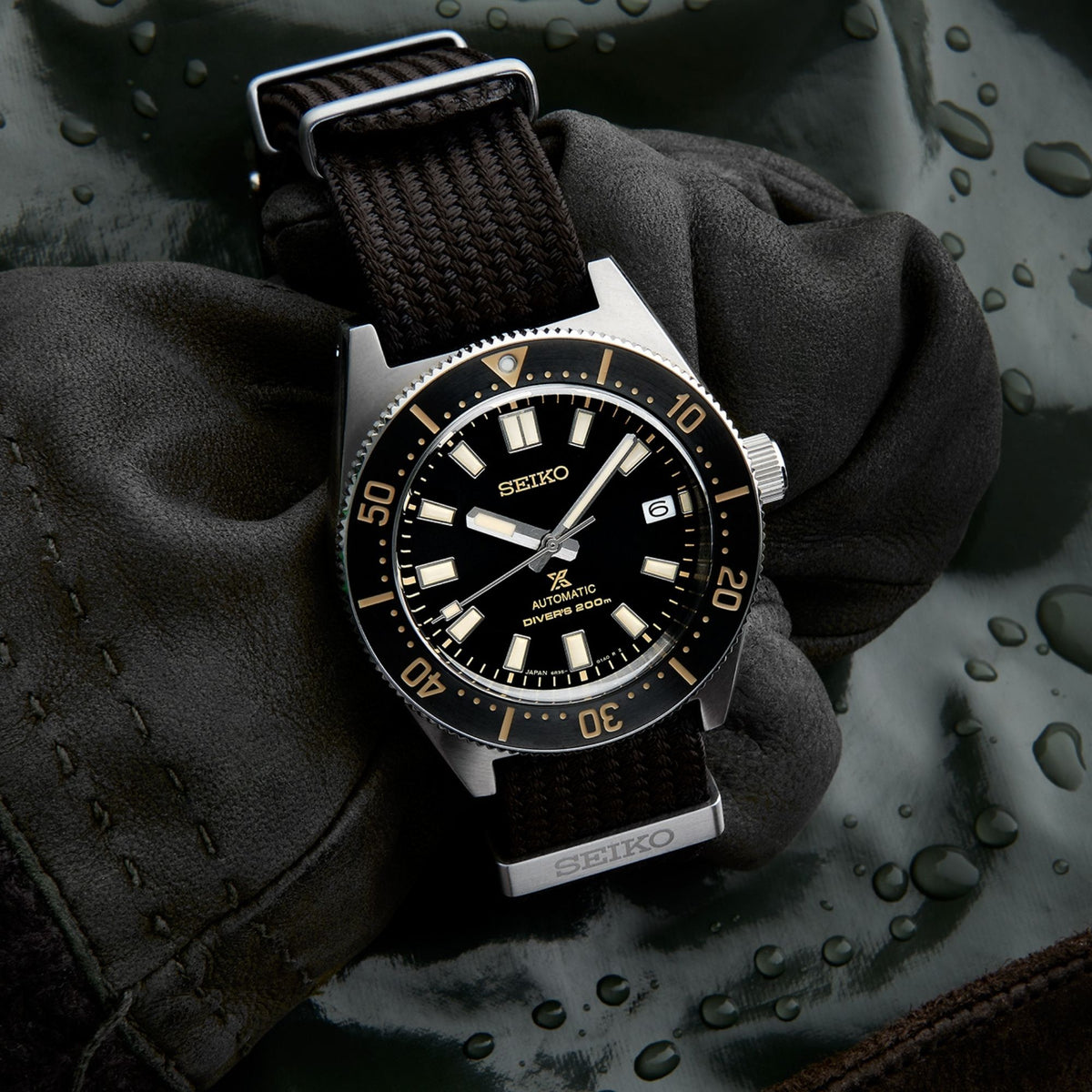 Men's Seiko diver watch on glove, black dial with gold indices and brown nylon strap