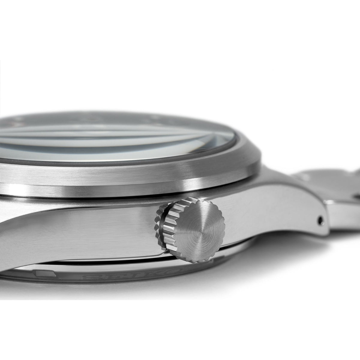 Stainless steel watch case side with ridged crown and black dial, close-up