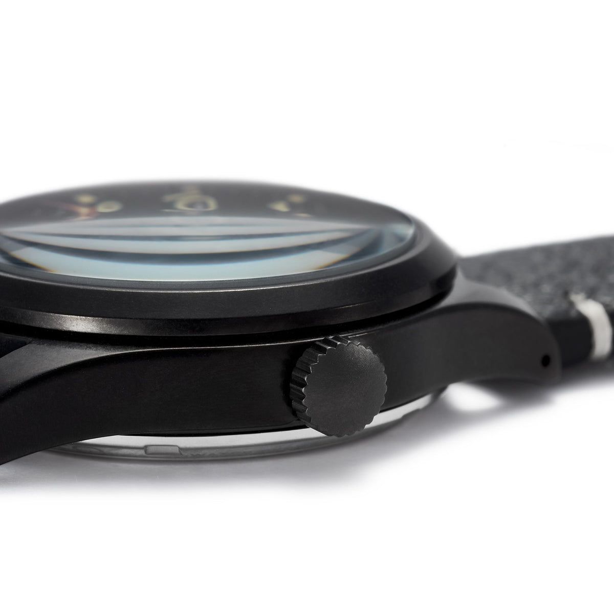 Black field watch side view showing crown and case edge, black dial, black leather strap