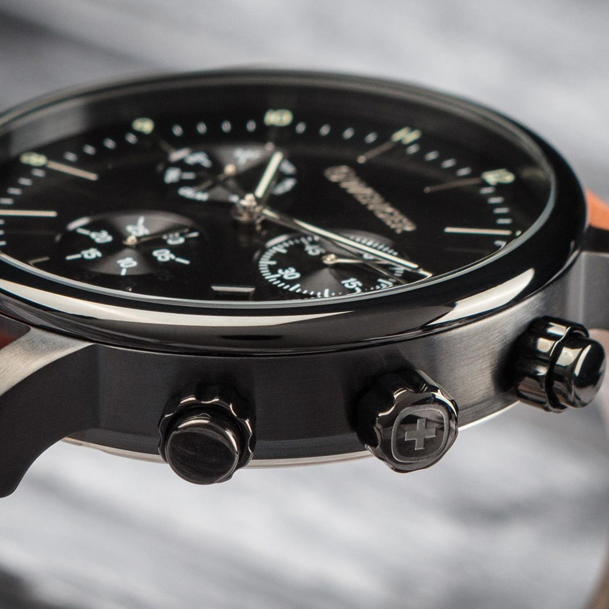 Men's chronograph watch side view with black dial edge, metal case, and pushers.