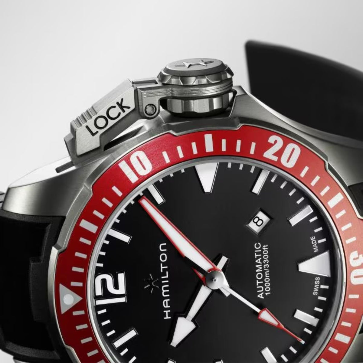 Macro view of black dial and red minute bezel with silver markers and hands