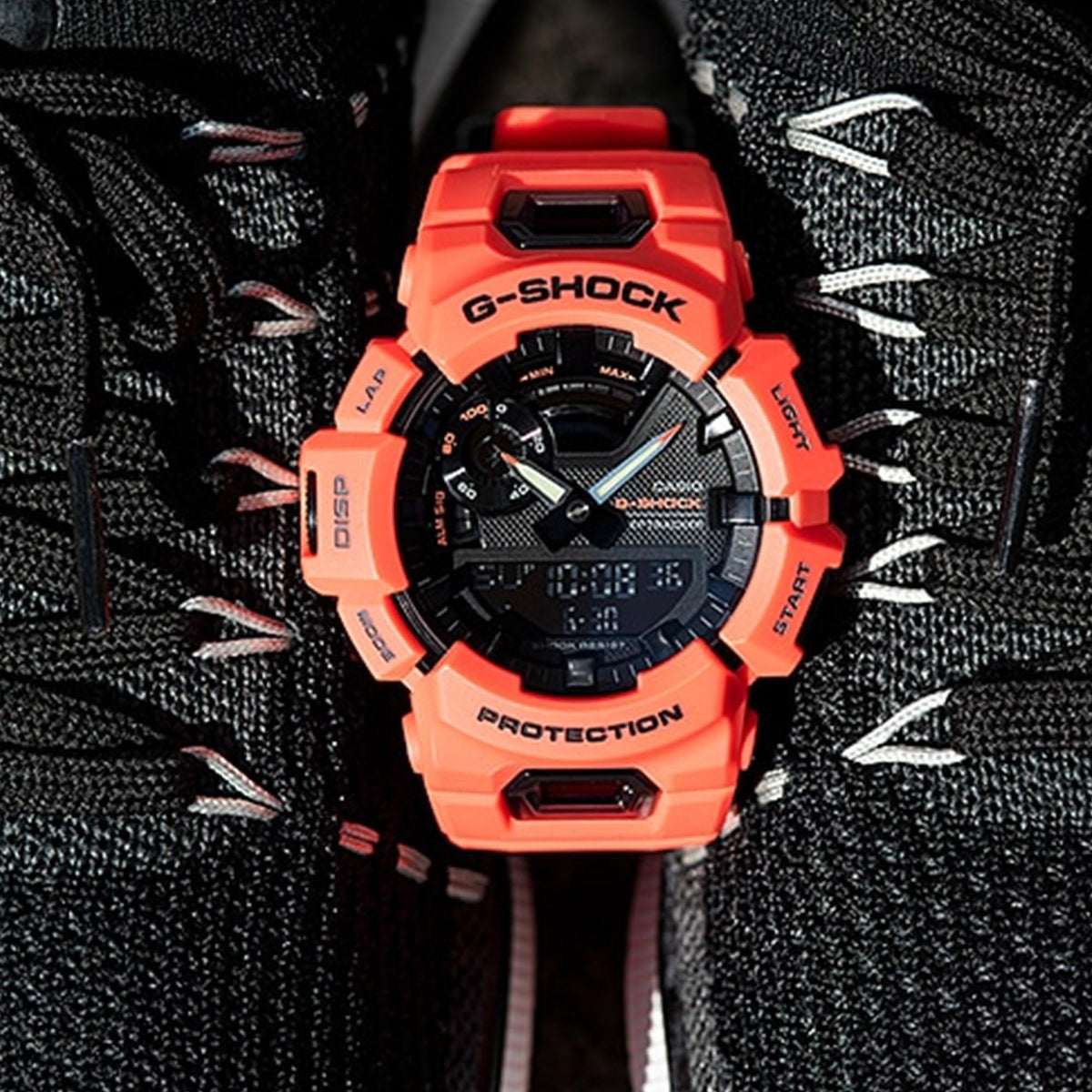 Casio G-Shock watch with red resin case and black dial, digital display visible.