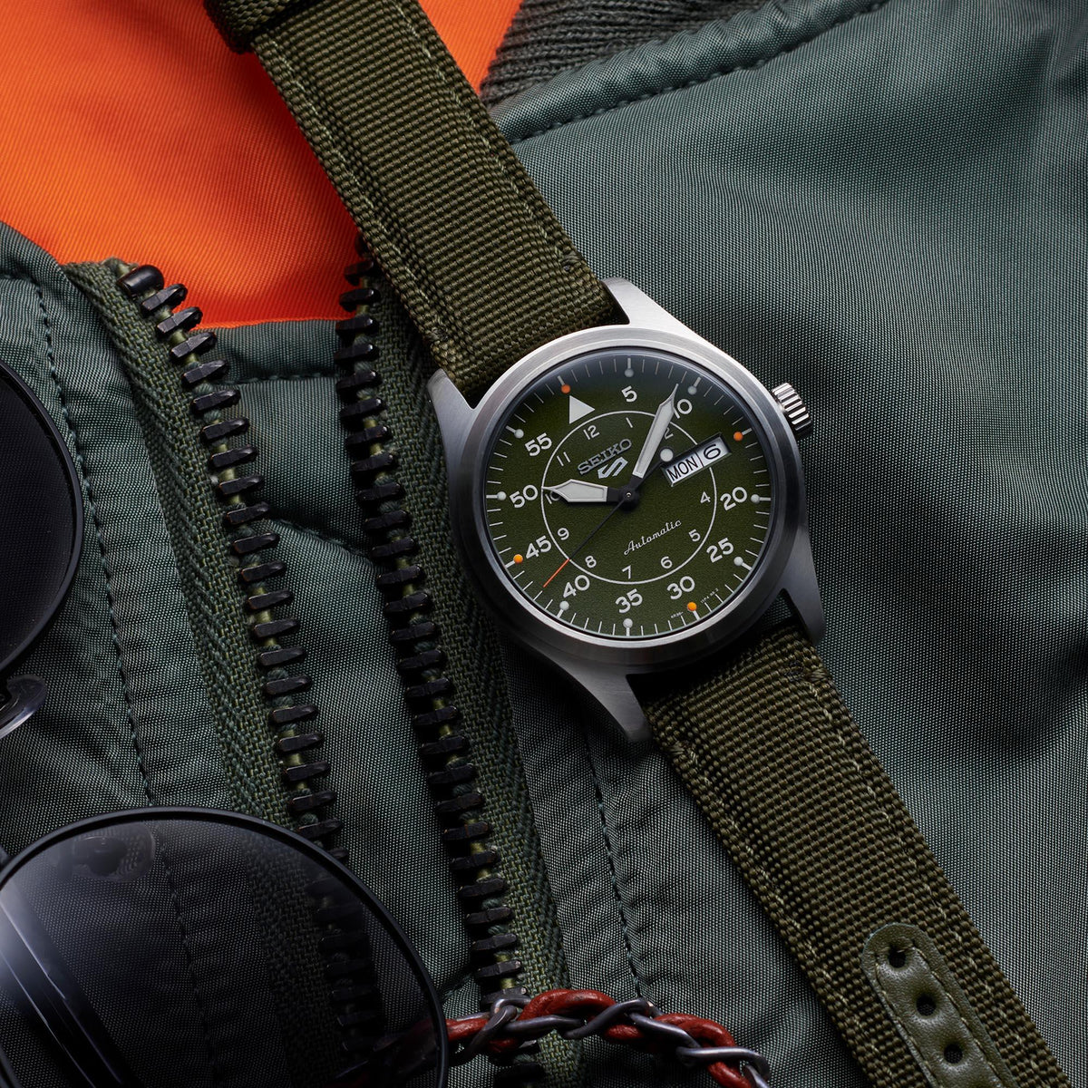Men's Seiko 5 Sports pilot watch with green dial and green nylon strap on jacket