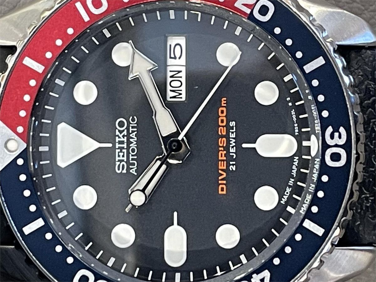 Close-up centering on the polished watch hands, arrow minute hand, and the luminescent markers.