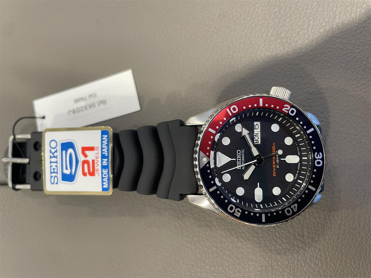Seiko SKX009J1 watch with black strap and Pepsi bezel on a gray surface