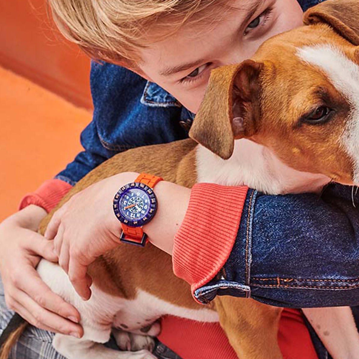 Children's wristwatch on wrist, orange silicone strap with dark blue watch face