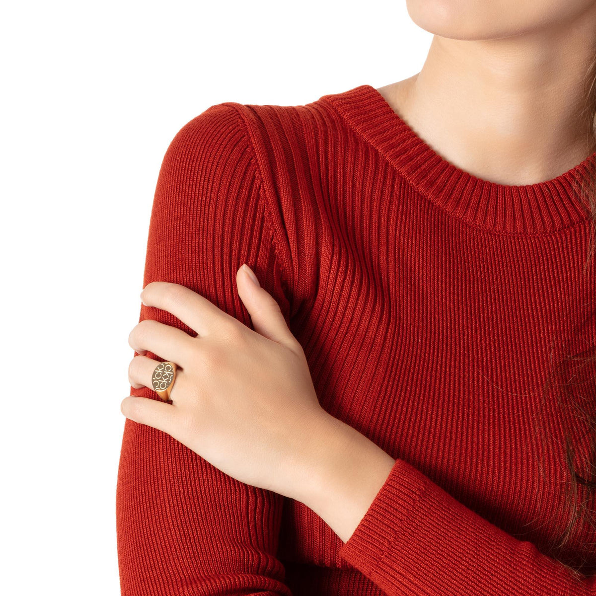 CK logo ring on finger with red knit sweater sleeve and cuff