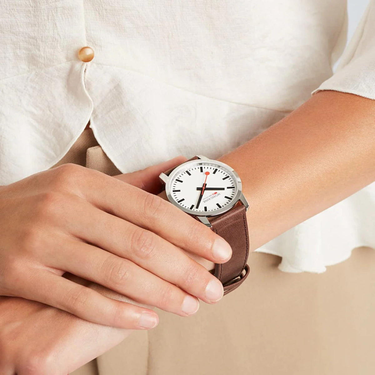 Men's wristwatch on arm with white dial and brown leather strap