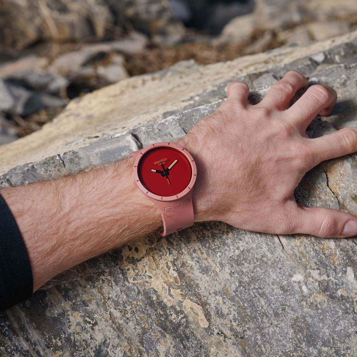 Red dial wristwatch on arm with light pink silicone strap