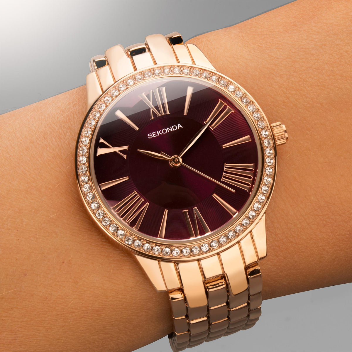 Ladies quartz watch on wrist with burgundy dial, rose gold-tone bracelet and stones