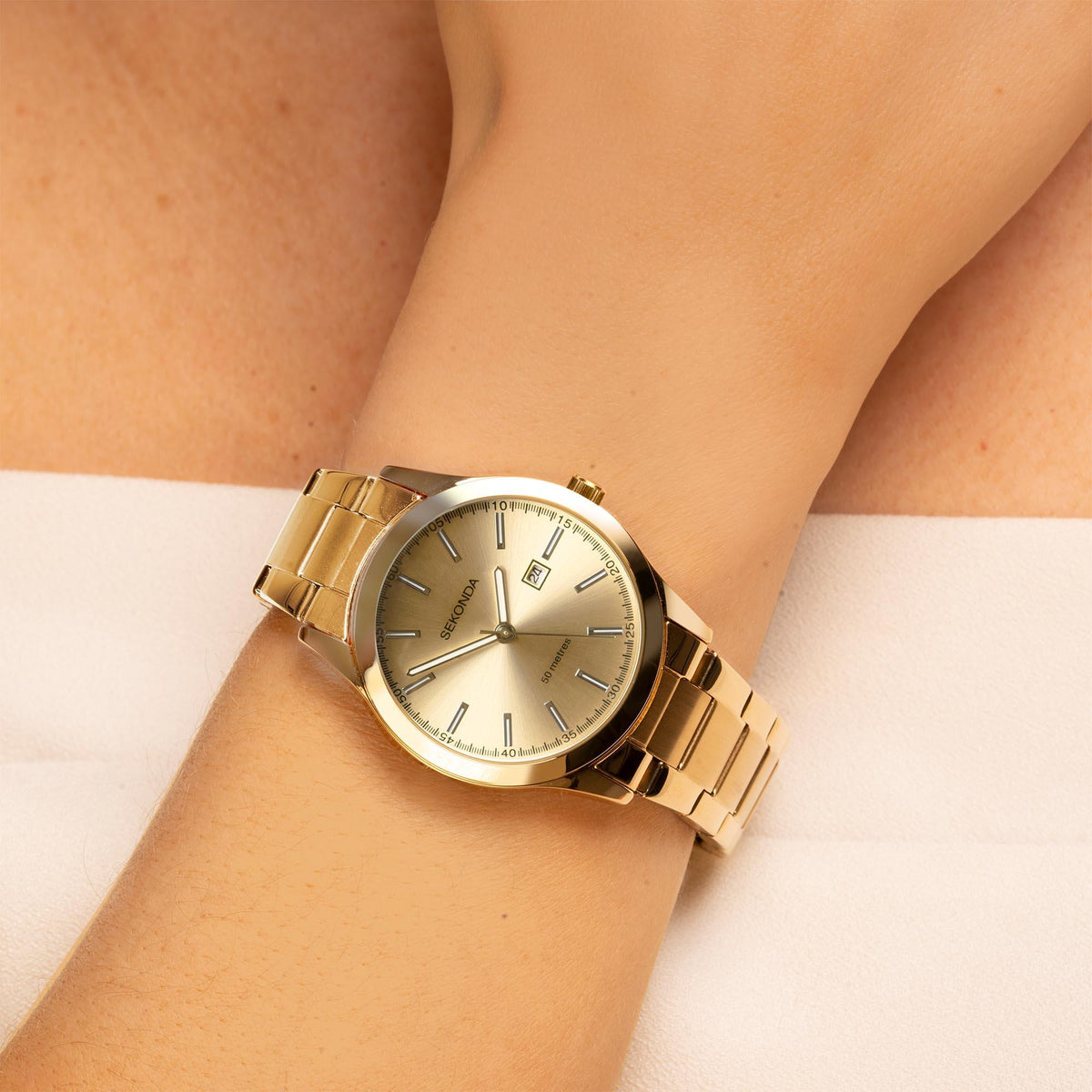 Gold-tone ladies quartz watch on wrist, champagne dial and metal bracelet with links