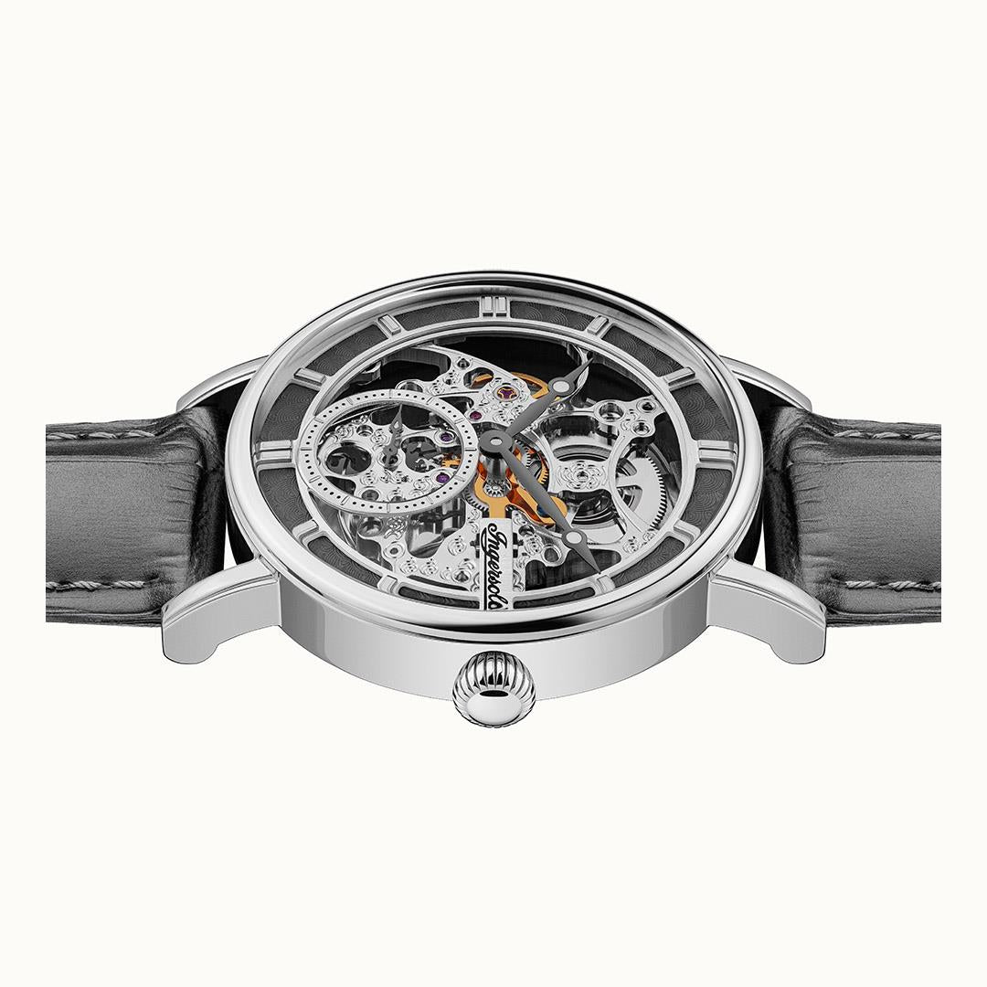 Front view of skeleton watch with exposed movement, silver case, and grey leather strap