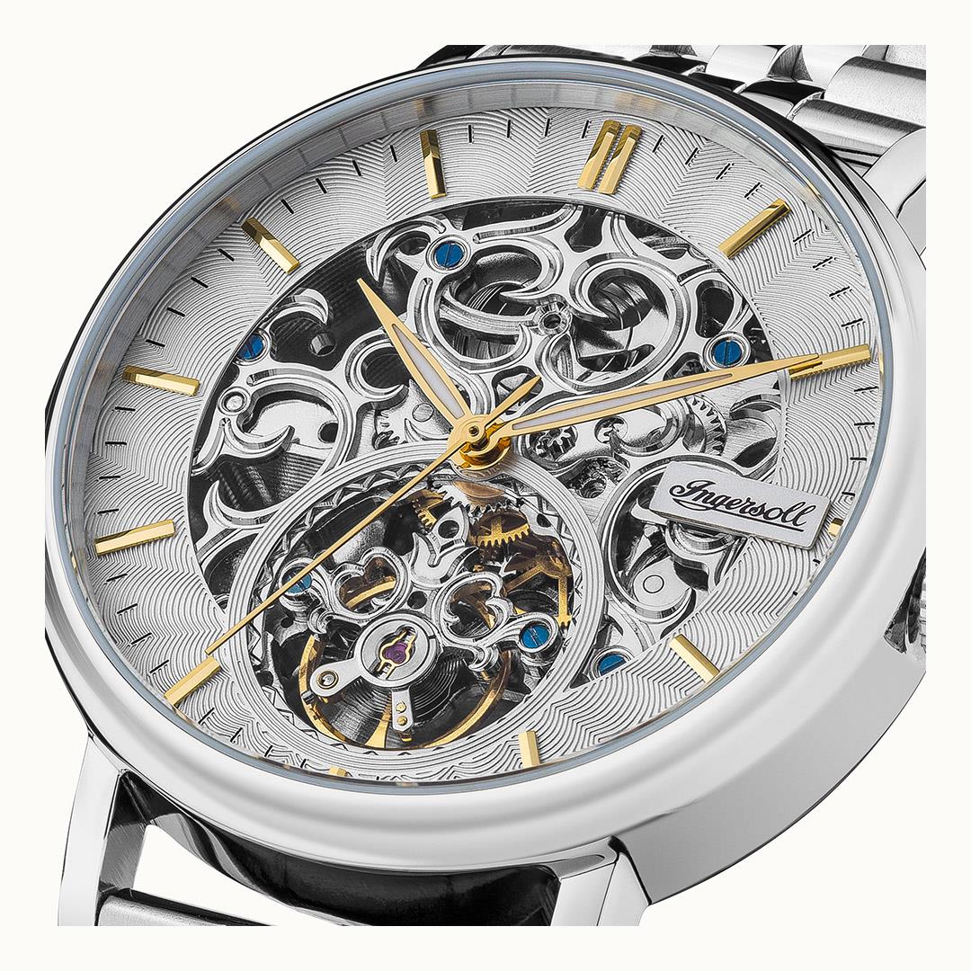 Automatic skeleton watch face close-up featuring silver movement, blue accents, and gold hands