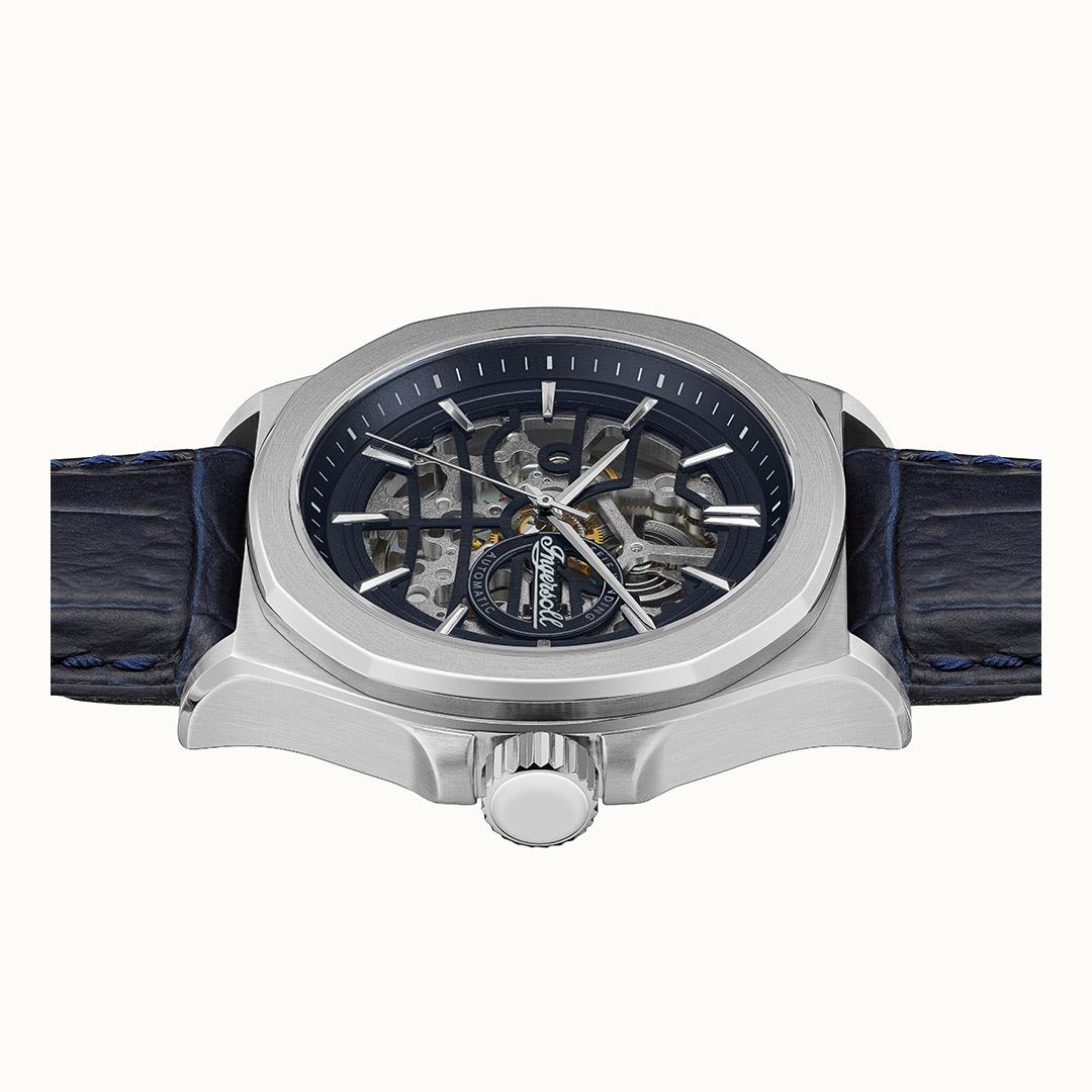 Automatic wristwatch showing navy skeleton movement and blue leather strap, visible crown