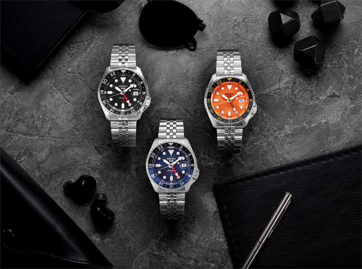 Three stainless steel GMT watches with blue dials and metal bracelets on display