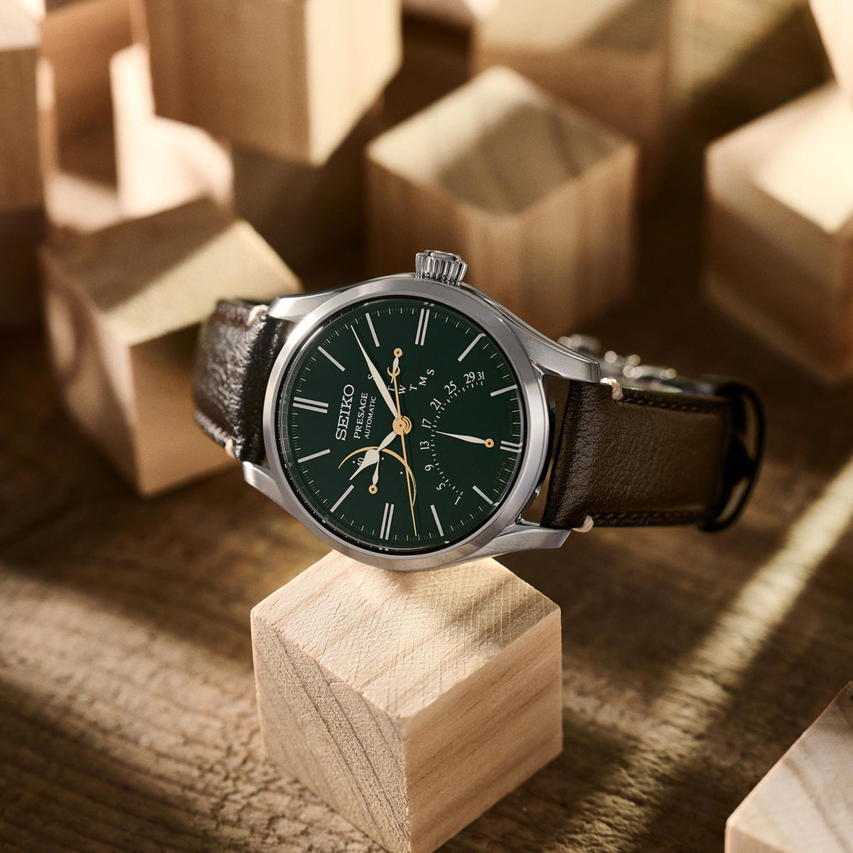 Men's automatic watch 3/4 view with green dial, black leather strap, and silver case