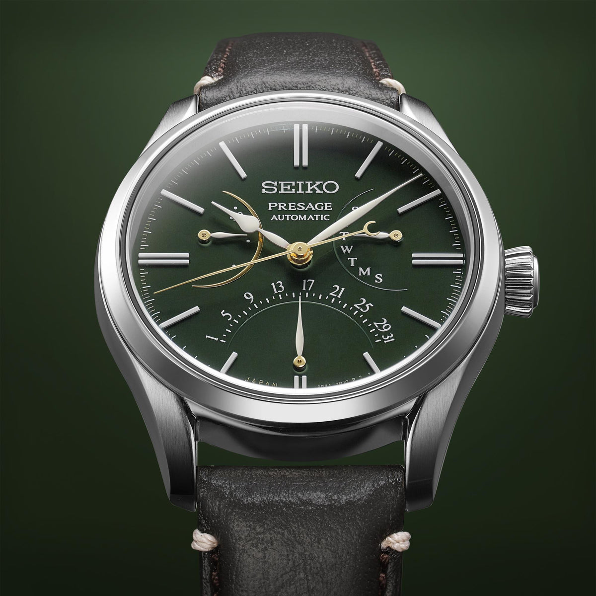 Men's automatic watch close-up with green dial, gold hands, and black leather strap