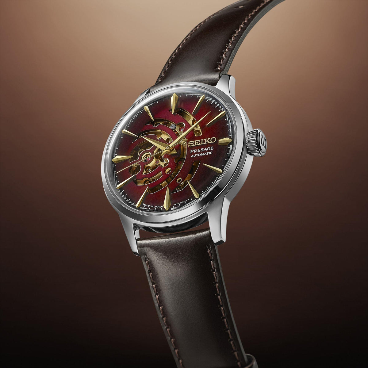 Men's automatic watch with red dial and gold-tone skeleton hands, black leather strap.