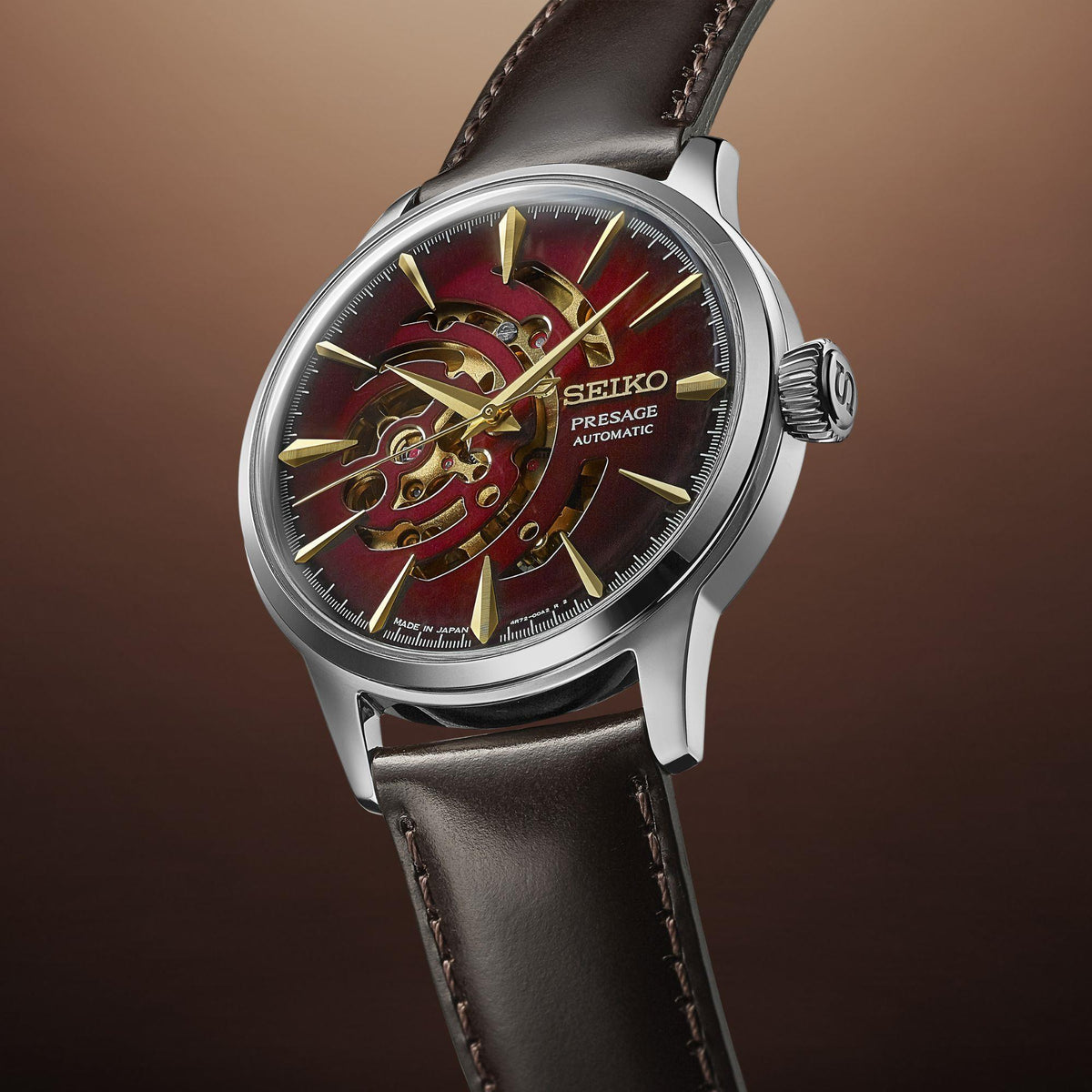 Men's automatic watch with red dial, gold-tone skeleton movement, black leather strap.