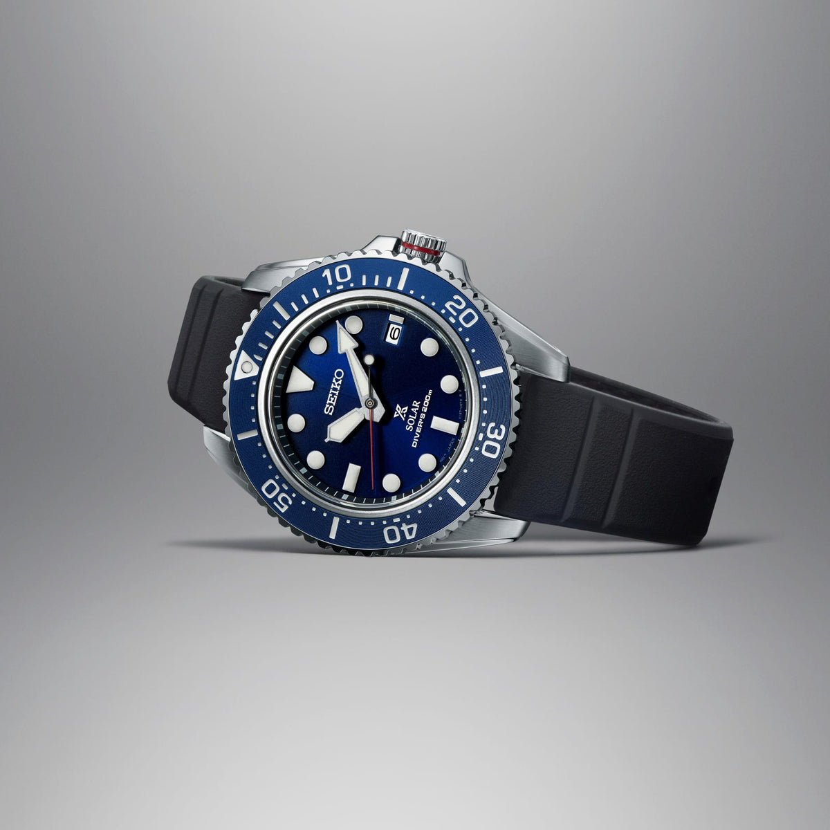 Men's solar diver watch in profile, blue bezel and dial, black rubber strap, steel case