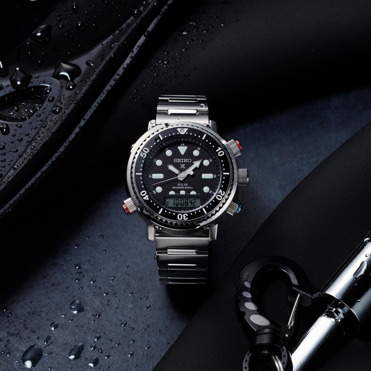 Stainless steel divers watch with black dial, metal bracelet, and colored bezel accents