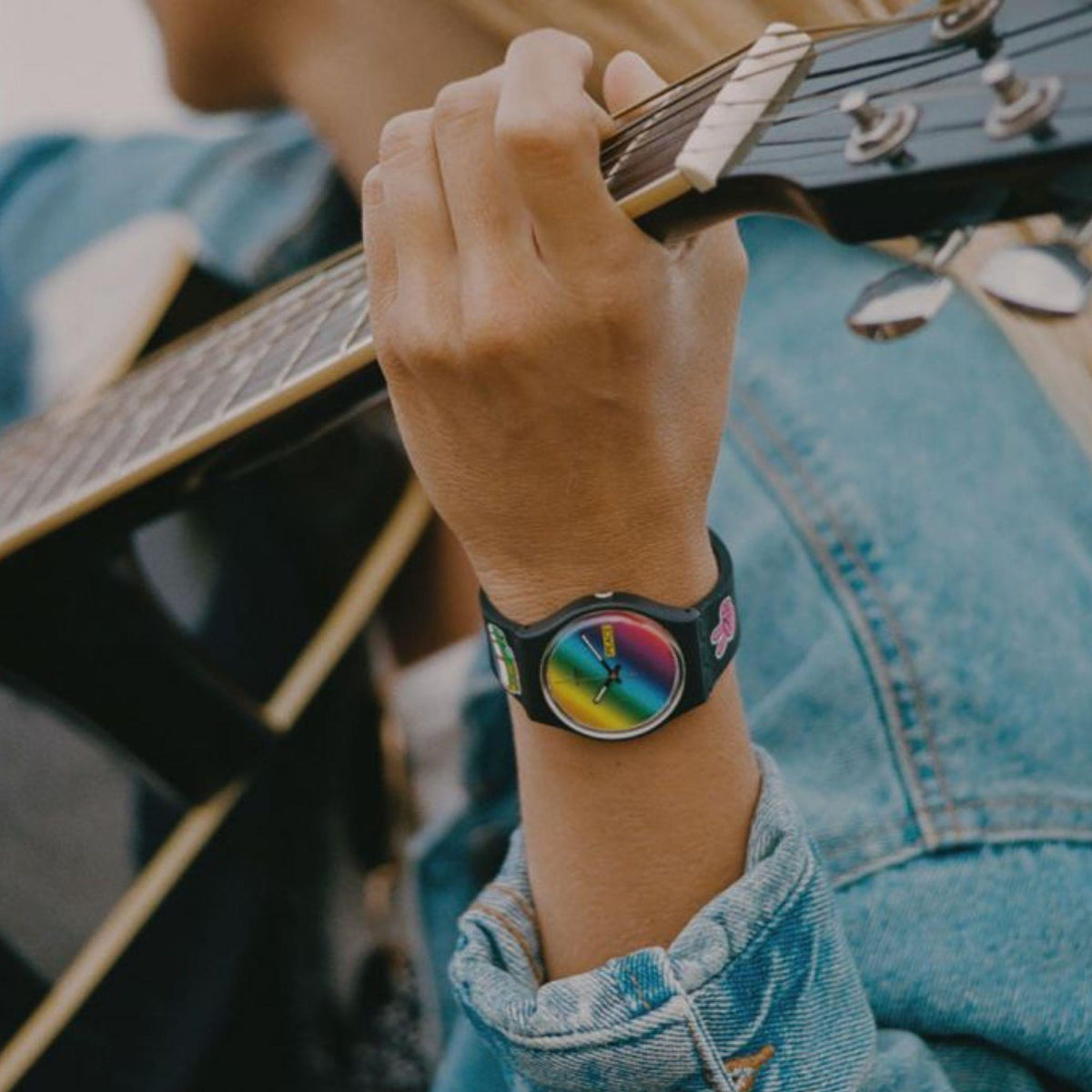 Black silicone quartz watch on wrist, multicolored rainbow dial with markers