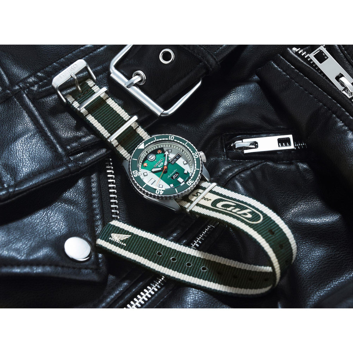 Automatic watch with green dial and striped NATO strap shown on black leather