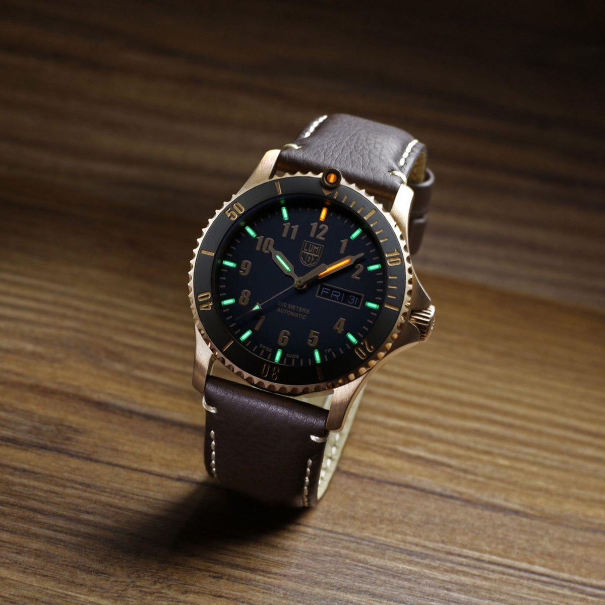 Men's automatic watch with black dial, green luminous markers, gold bezel, brown leather strap