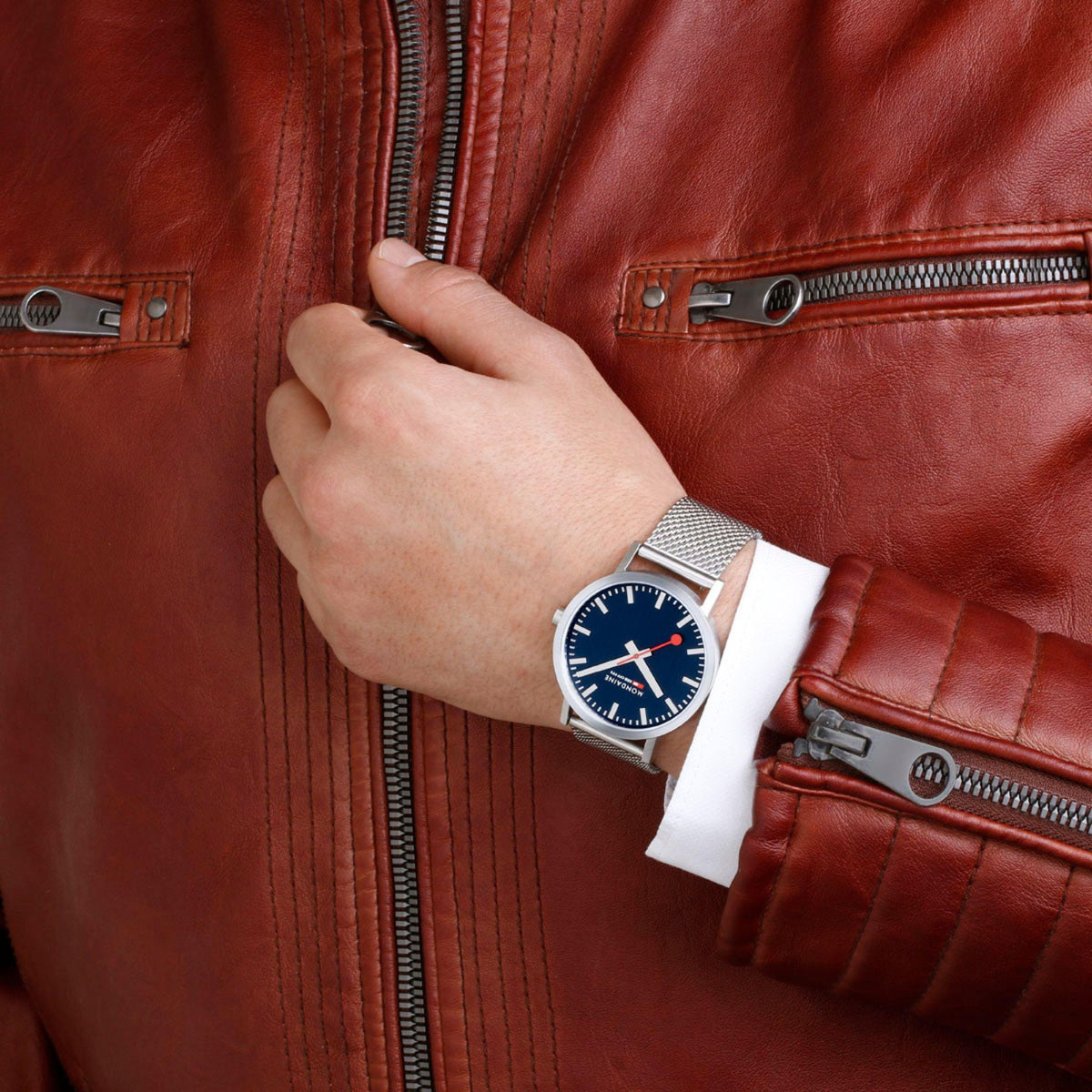 Mondaine steel-cased blue dial watch with white leather strap on wrist
