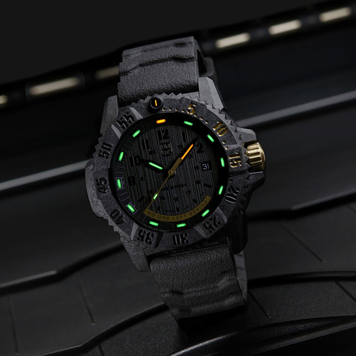 Men's black dial watch with green glow markers and gray rubber strap, gold accents