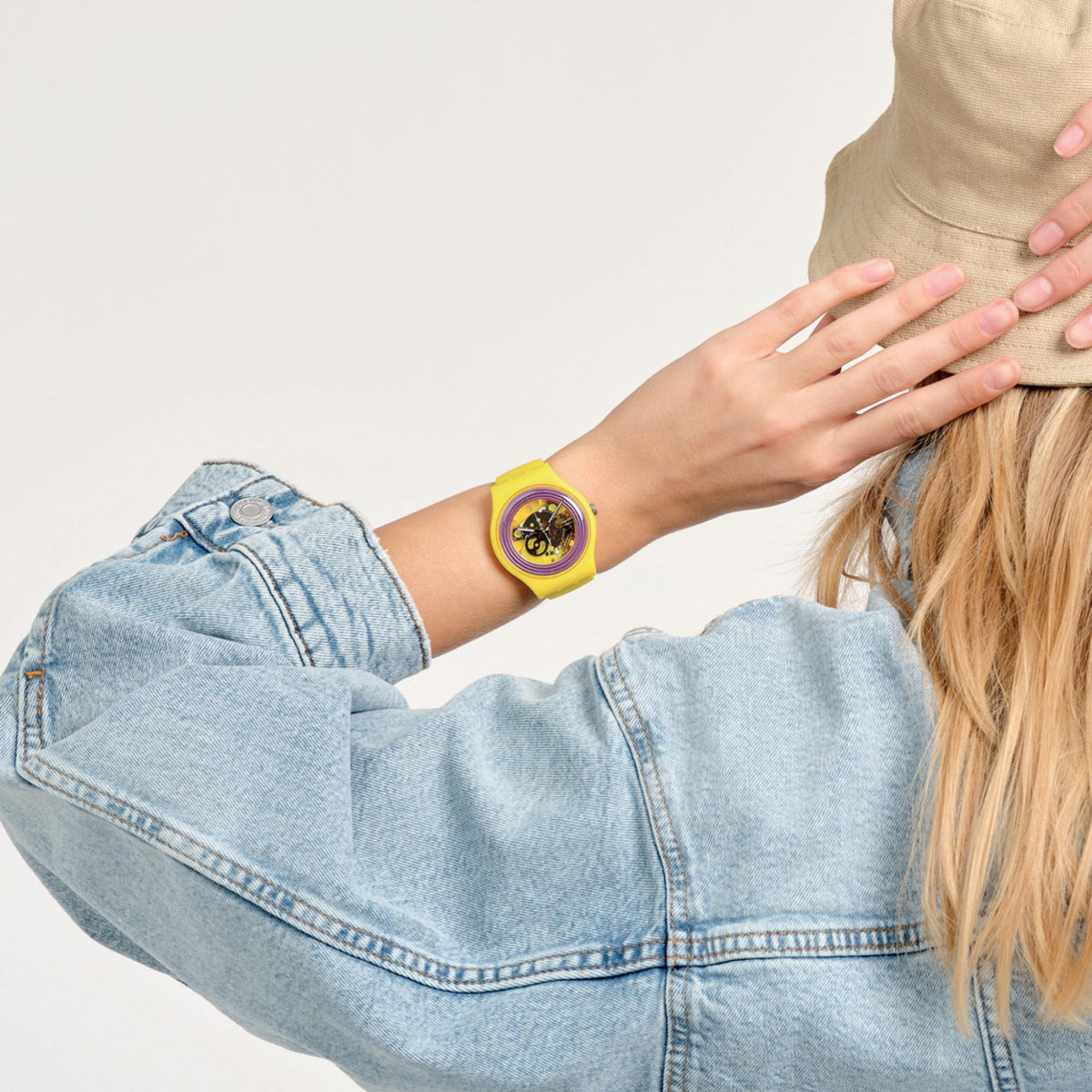 Swatch quartz wristwatch with yellow bezel and purple ring dial, worn on wrist