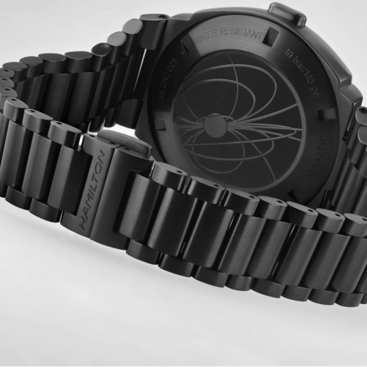 Black steel watch bracelet and case back detail with water-resistant text