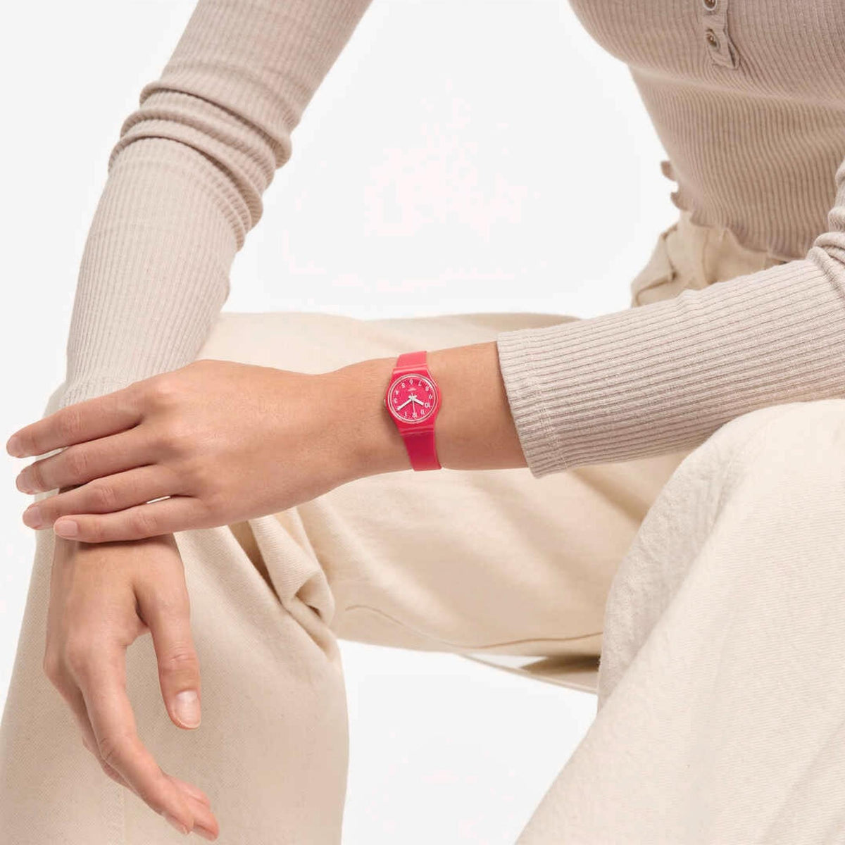 Pink silicone strap watch on wrist with round dial visible under sleeve cuff