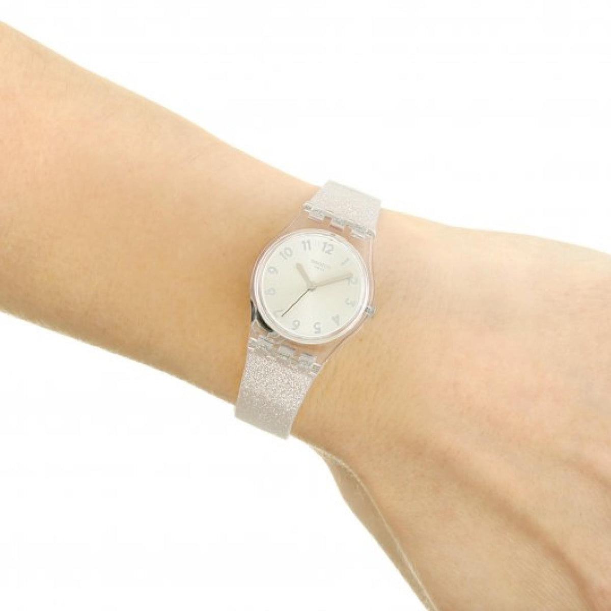Silver-toned round ladies wristwatch with glitter clear strap on a wrist