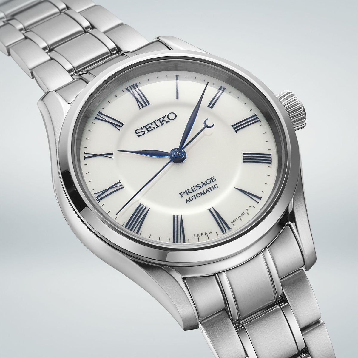 Close-up of men's stainless steel watch face with white dial and blue Roman markers