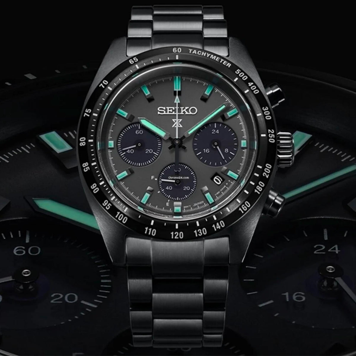 Black chronograph dial with turquoise hands and markers, steel bracelet