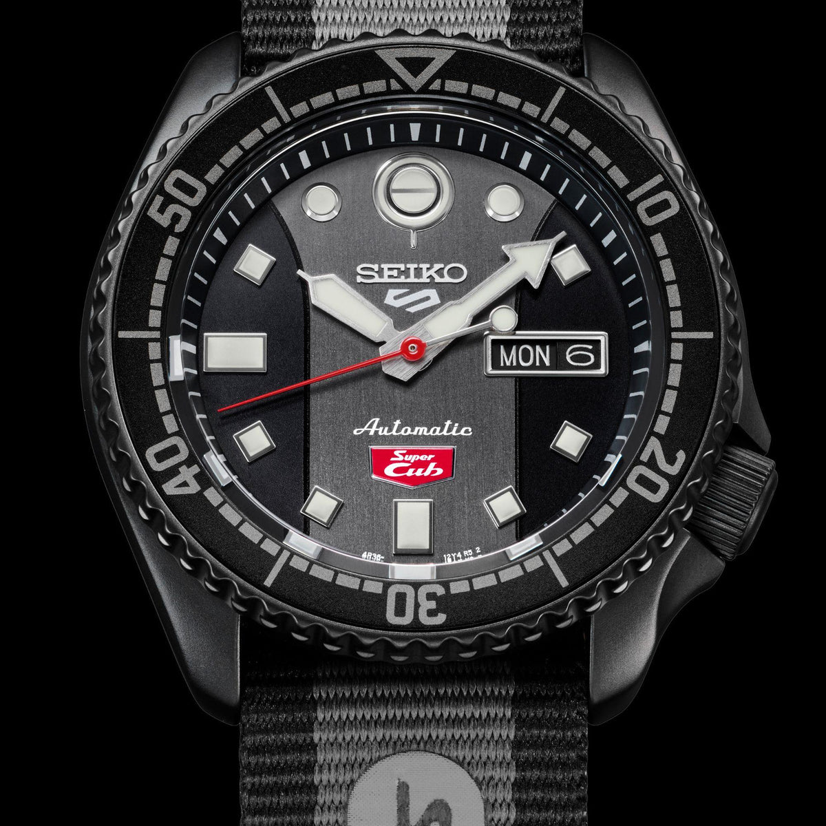 Men’s automatic watch close-up: black dial with MON 6 date, gray NATO strap