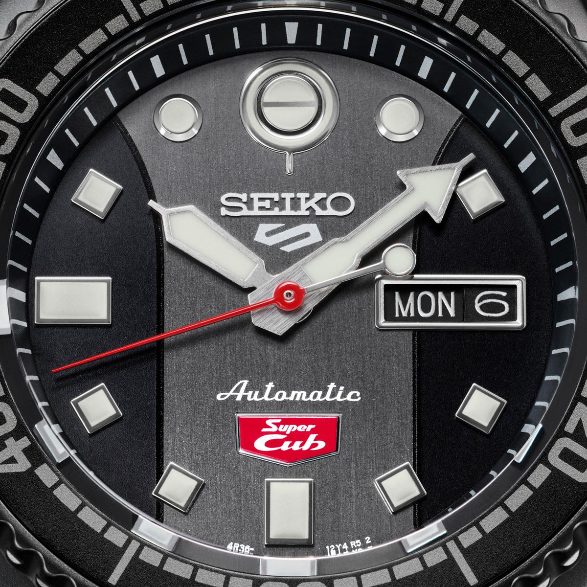 Men’s automatic watch dial close-up showing MON 6 date window and red seconds hand