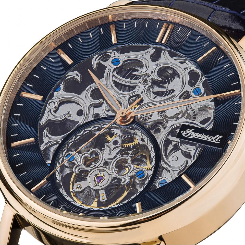 Close-up of men's skeleton watch dial with blue accents and rose-gold rim around movement