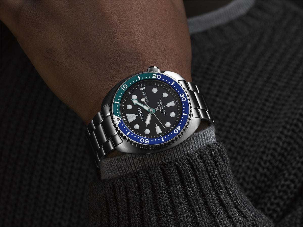 Men's stainless steel diver watch on wrist, black dial with luminous markers and green accents