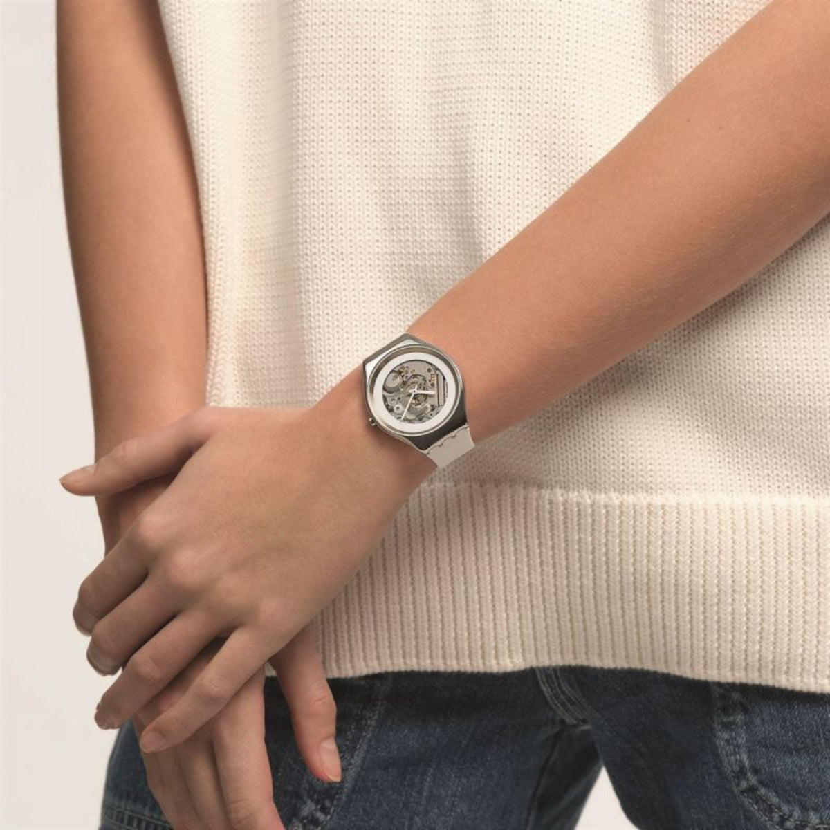 Men's wristwatch on wrist with white strap; skeleton dial on silver case