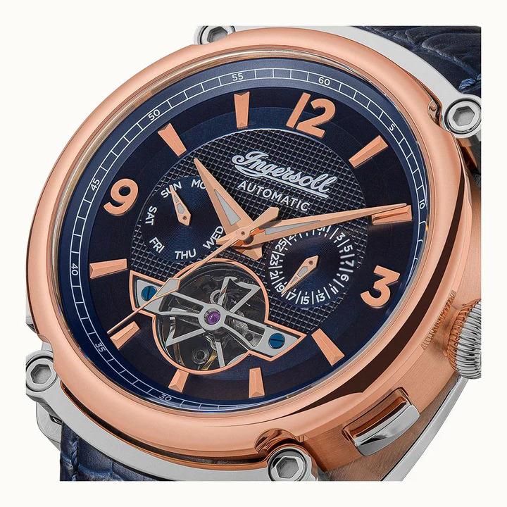 Close-up dial view with blue face, rose-gold bezel, orange indices, openwork movement