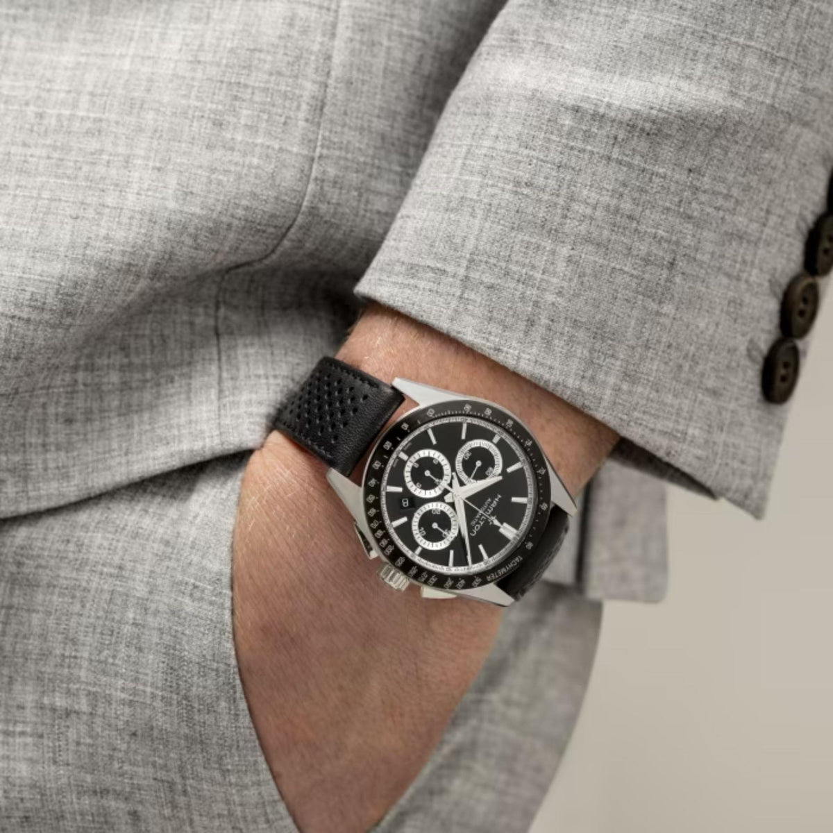 Men's chronograph watch on wrist with black dial, black leather band, metal buckle.