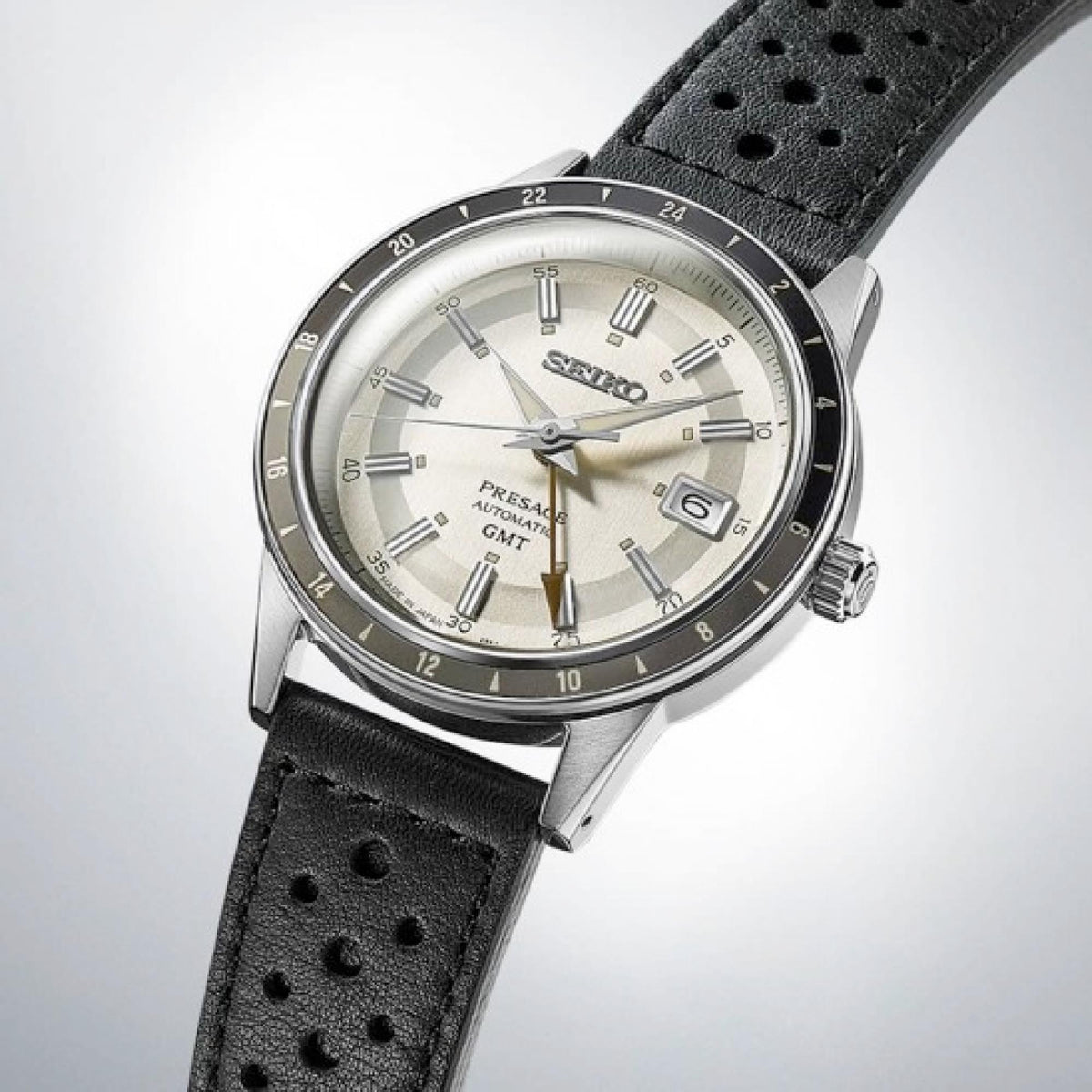 Men's GMT automatic watch angled view with silver dial, black bezel, and black perforated leather strap